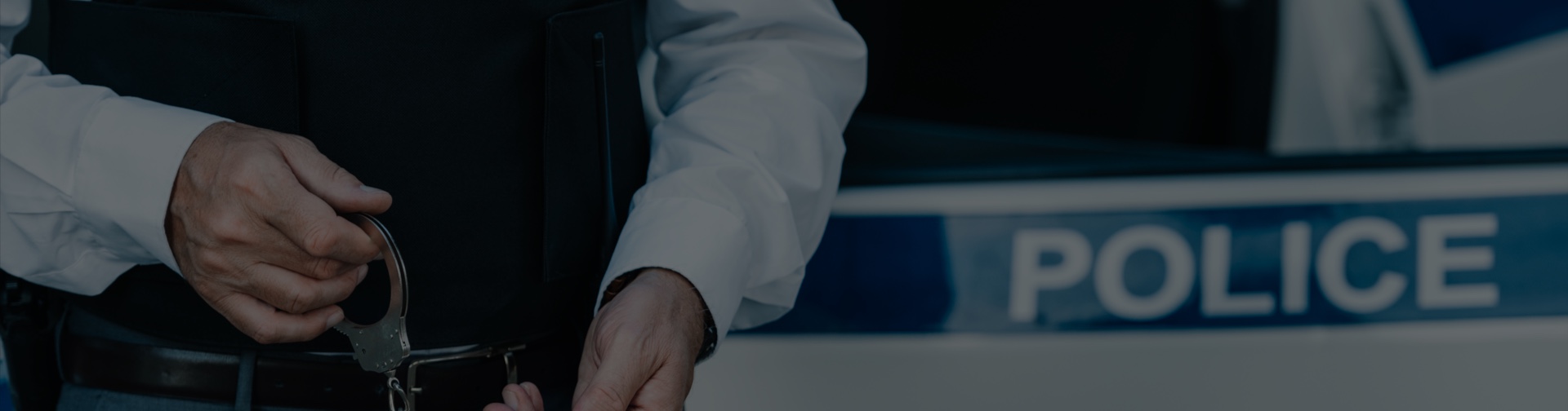 Policier en train de menotter une personne devant une voiture de police, symbolisant l’intervention possible d’un avocat spécialisé en alcool au volant.