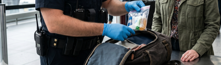 Policier portant des gants bleus fouillant le sac d'une personne et inspectant des objets personnels